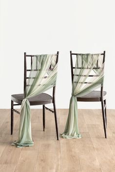 two chairs with drapes on them sitting in front of a white wall and wooden floor