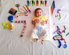 a baby laying on the floor surrounded by crayons and markers