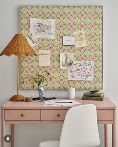 a pink desk topped with a white chair next to a wall covered in pictures