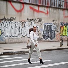 a woman crossing the street in front of graffiti