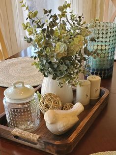 a wooden tray topped with vases filled with flowers and other items on top of a table