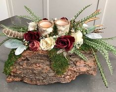 a vase filled with flowers and candles on top of a piece of drifty wood