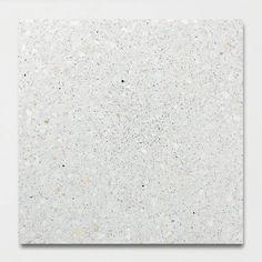 a white square tile with speckles on it