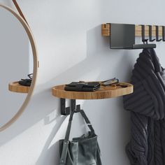 a mirror and coat rack on the wall next to a handbag hanging from a hook