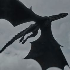 a large black dragon flying through the sky