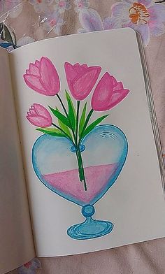 an open book with watercolors and flowers in the shape of a heart on it