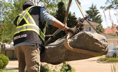 a man in safety vest lifting a large rock