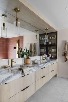 a bathroom with marble counter tops and pink tiles on the walls, along with brass fixtures