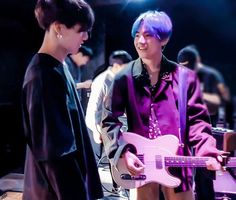 two young men standing next to each other with purple hair and one holding a pink guitar