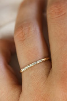 a woman's hand with a gold band and diamond ring on her left hand