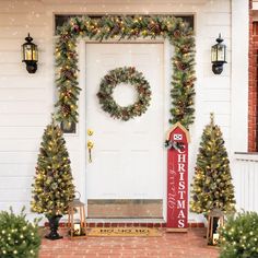 two christmas wreaths on the front door of a house with holiday decorations around it