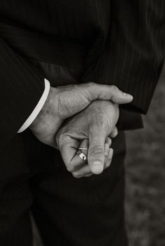 an older man and woman holding hands in black and white