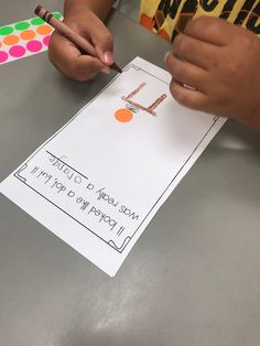 a child is making a letter l craft with scissors and paper on the table in front of them