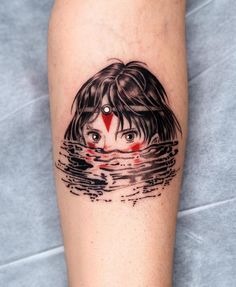 a woman's leg with a black and white tattoo on it, which has a red triangle in the water