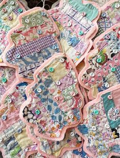 several patchwork baby bibs are laying on the floor together with buttons in them