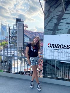 a woman standing in front of a stadium sign