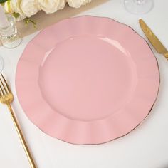 a pink plate sitting on top of a table next to silverware and flowers in vases