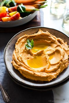 hummus on a plate with vegetables in the background