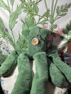 a green stuffed animal sitting on top of a table