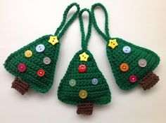 three crocheted christmas trees with buttons on them