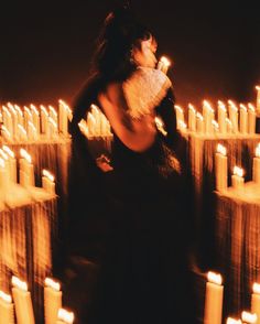 a woman standing in front of many lit candles