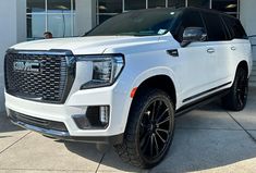 a white truck parked in front of a building with black rims and tires on it