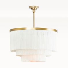 a chandelier hanging from the ceiling with white pleated fabric and gold trim