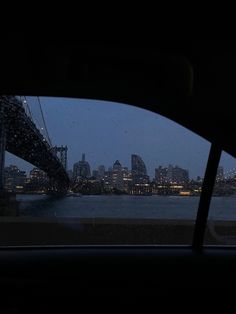 the view from inside a car looking at a bridge and city lights in the distance