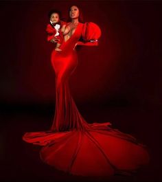 a woman in a red dress holding a baby