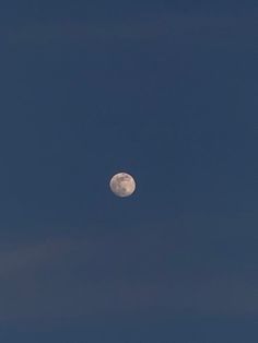 the full moon is visible in the blue sky