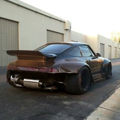 a brown sports car parked in front of a garage door on the side of a road