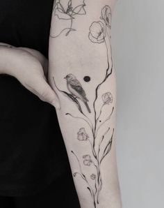 a woman's arm with flowers and two birds on it, one is black and white