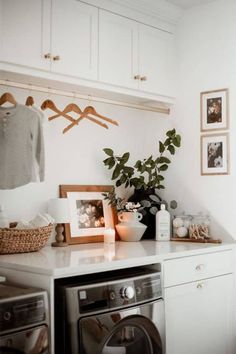 a washer and dryer in a room with pictures on the wall above it