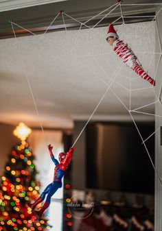 the spider man is hanging upside down in front of the christmas tree