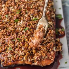 a piece of meat covered in pecans and garnished with a fork