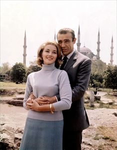 a man and woman standing next to each other in front of a building with blue domes