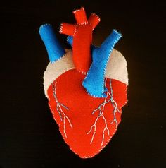 a red and blue stuffed heart on a black surface with white stitching around it