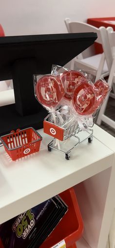 a display case filled with red candies on top of a white table next to chairs