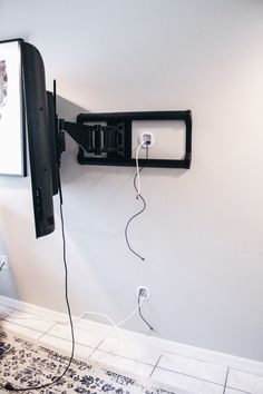 a flat screen tv mounted to the side of a wall next to a plugged in charger