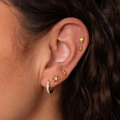 a close up of a person's ear with three small gold studs on it