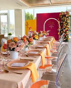 a long table set up with place settings and flowers in vases on the tables