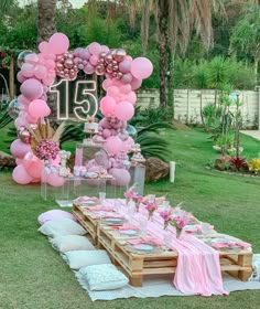 a table set up with pink balloons and decorations for a 21st birthday party in the garden