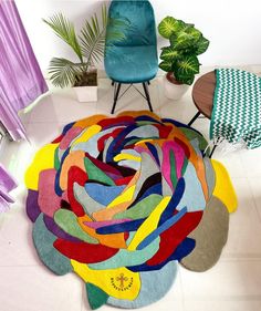 a multicolored rug on the floor next to a chair and potted plant