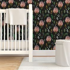 a white crib in front of a black wallpaper with pink flowers on it