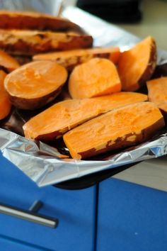 some cut up sweet potatoes sitting on top of tin foil in front of an oven