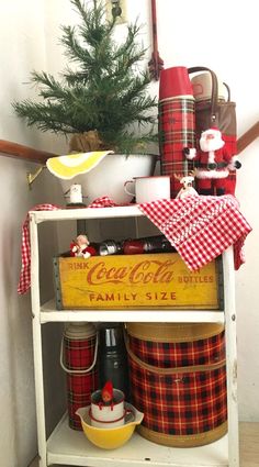 a shelf with coca - cola cans and other items on it, along with a christmas tree