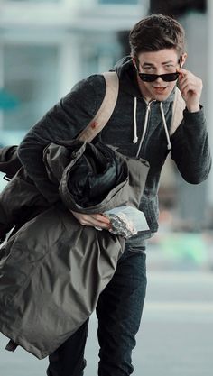 a man walking down the street with his hand in his pocket and wearing sunglasses on top of his head