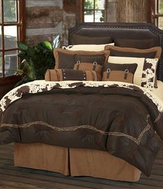 a bed with brown and white comforters in a room next to a wooden floor