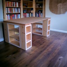 a wooden desk sitting on top of a hard wood floor next to a book shelf