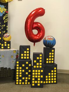 a number six balloon sitting on top of blocks in the middle of a room filled with balloons